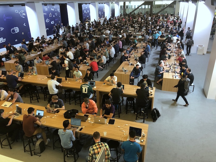 Hundreds of iOS Developers working on laptops at long tables